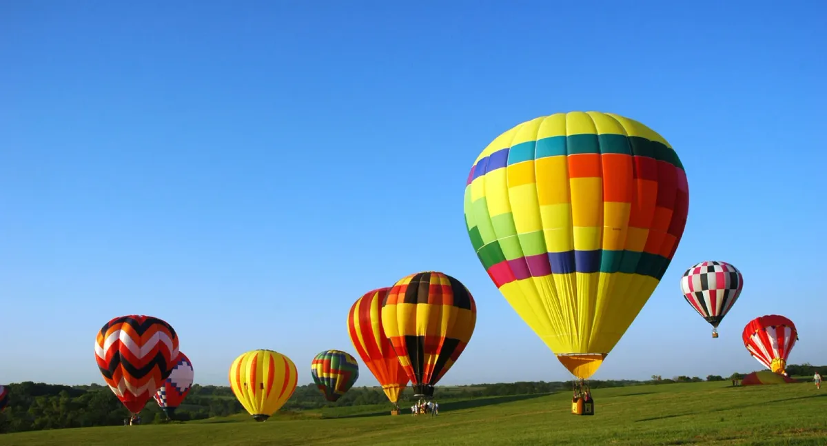 A hot air balloon rising at sunrise above the vineyards of Napa Valley, California with mountains in the background